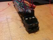 A new approach: 30 awg wires directly threaded through the plastic for 0.1" headers. Here, superglue attaching the bar to the locomotive base drying